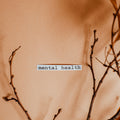 Text 'mental health' on a blurred background with branches.